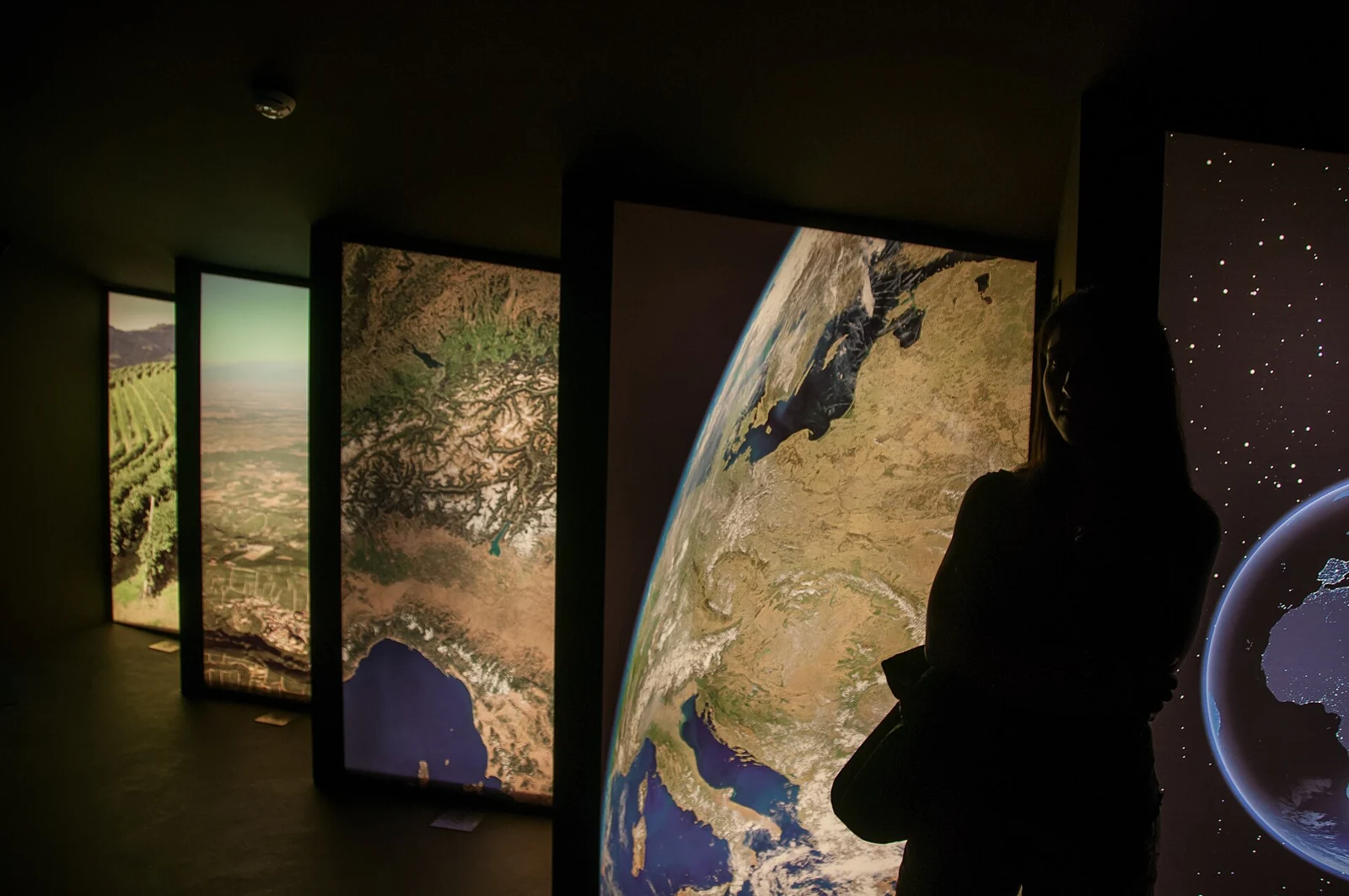 A visitor looking at illuminated displays inside WiMu in Barolo