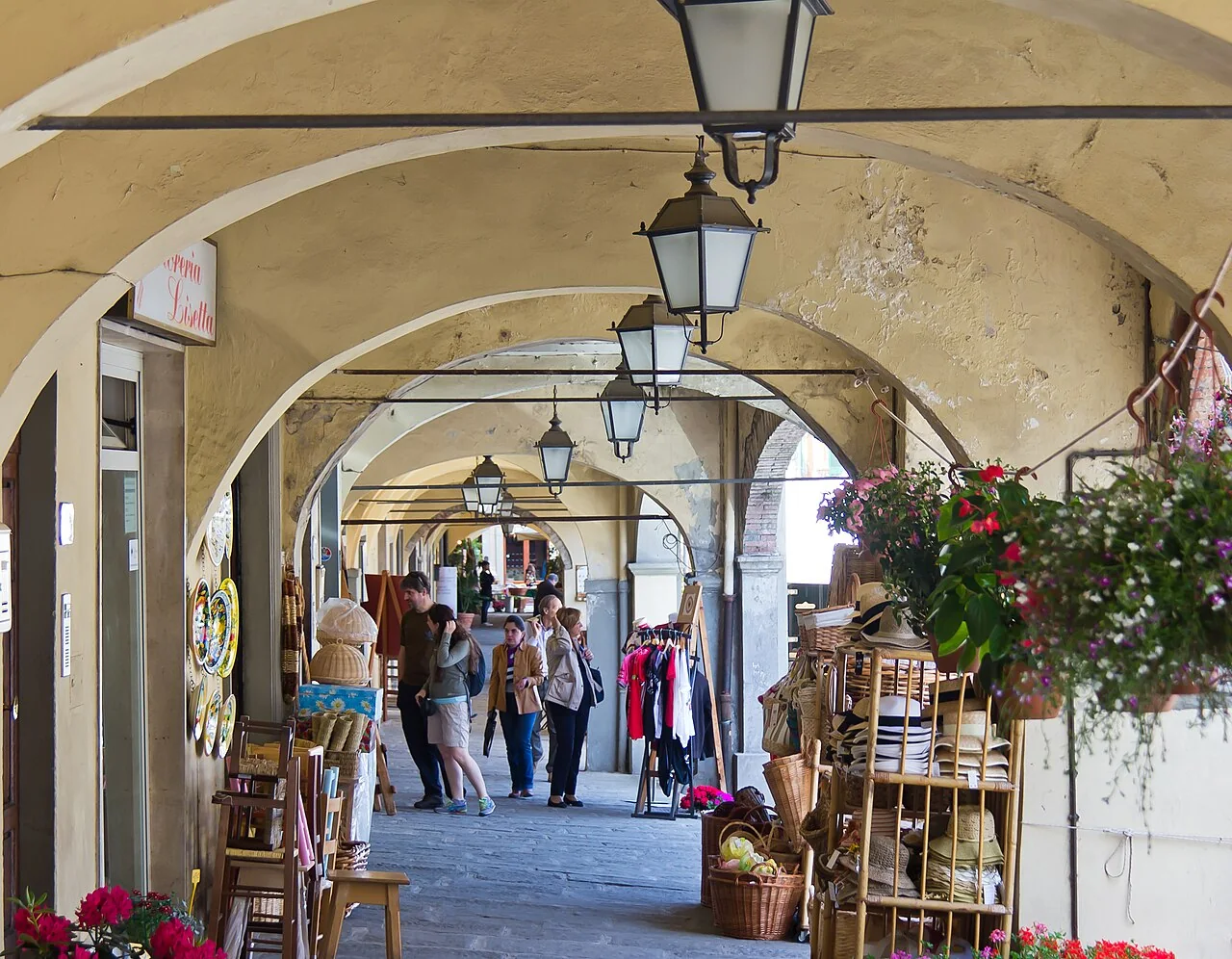 Visitors browsing shops beneath the covered arcades of Piazza Giacomo Matteotti in Greve in Chianti